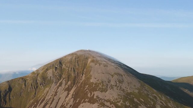 Amazing 4K aerial video of flying above and around Most Famous mountain in Ireland - Croagh Patrick in windy weather, with moving fog and clouds with breathtaking views around, Westport, Ireland