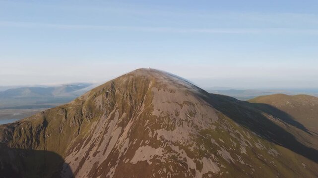 Amazing 4K aerial video of flying above and around Most Famous mountain in Ireland - Croagh Patrick in windy weather, with moving fog and clouds with breathtaking views around, Westport, Ireland