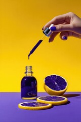 A hand with purple nail polish pours deep purple liquid from a dropper into a glass bottle;  half a purple citrus fruit and slices rest on a purple surface against a yellow background