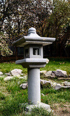 Traditional white stone Japanese pagoda lantern in garden with green lawn background, zen decoration sculpture