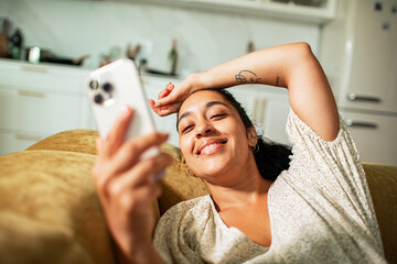Young woman smiling while using smartphone at home
