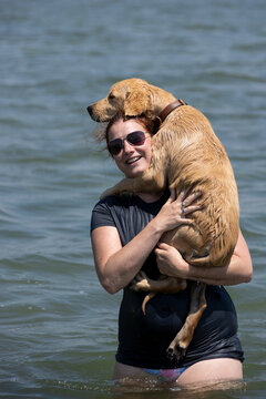 Woman carrying a big dog in a lake