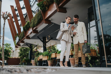 Business partners reviewing project details using tablet in a modern outdoor setting