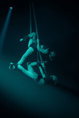 Two female aerialists perform a counterbalanced duo on hanging steel chains&mdash;vertical frame; suspended acrobatic pose with strong grip and clean lines.
