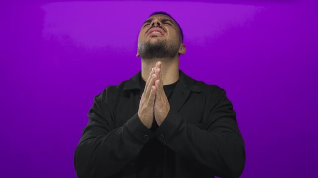 Man grimacing and covering ears against intense blaring noise in purple studio; sensory overload distress.