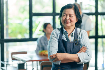 Asian woman cafe owner standing with confident smile wearing apron inside restaurant, successful...