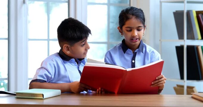 Indian School Kids Studying Together from Book in Classroom While Wearing School Uniforms, Engaging in Group Learning, Reading, Sharing Knowledge in Academic Session Focused on Education, Teamwork