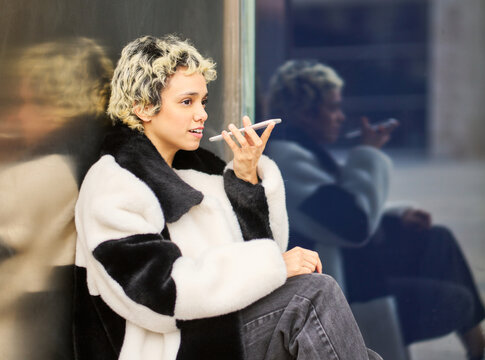 Young woman recording voice message on smartphone