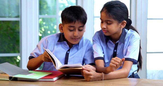 Indian School Kids Studying Together from Book in Classroom While Wearing School Uniforms, Engaging in Group Learning, Reading, Sharing Knowledge in Academic Session Focused on Education, Teamwork