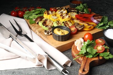 Vegetarian barbeque. Tasty grilled vegetables served with sauce on grey table