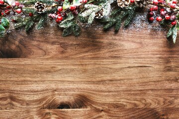 Festive holiday decoration with pine cones, red berries, and evergreen branches on a wooden table. Rustic and natural holiday decor with pine and berries. Wood texture background. Christmas background