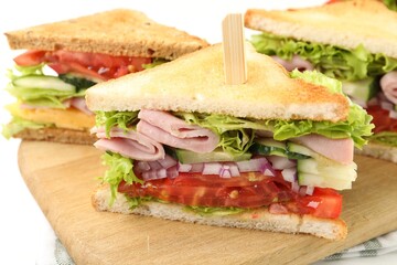 Tasty sandwiches with ham and vegetables on white table, closeup