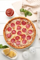 Delicious pepperoni pizza and ingredients on white wooden table, flat lay