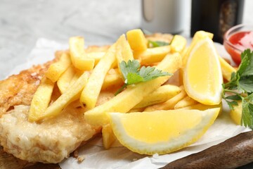 British Traditional Fish and chips with lemon and parsley on gray table, closeup