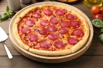 Delicious pepperoni pizza, server and ingredients on wooden table
