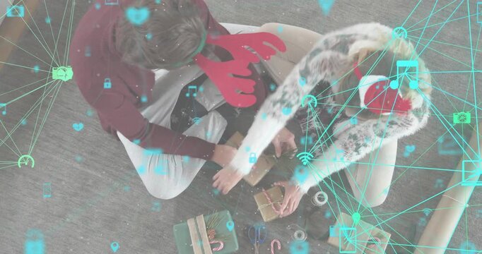 Couple placing kraft box starting wrapping looping twine adding candy cane sprig and grouping gifts