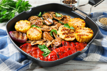 Delicious grilled vegetables with mushrooms in pan and spices on table, closeup