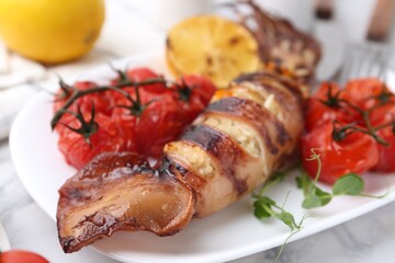 Tasty stuffed squid, microgreens and tomatoes on white marble table, closeup