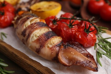 Tasty stuffed squid, rosemary and tomatoes on table, closeup