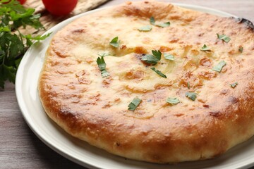 Delicious Megrelian khachapuri with parsley on wooden table, closeup