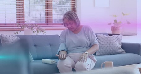 Senior woman positioning blood pressure cuff and monitoring reading while checking wristwatch - Powered by Adobe