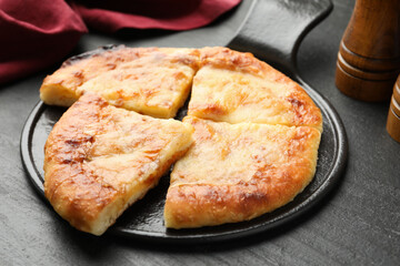 Cut delicious Megrelian khachapuri on black table, closeup