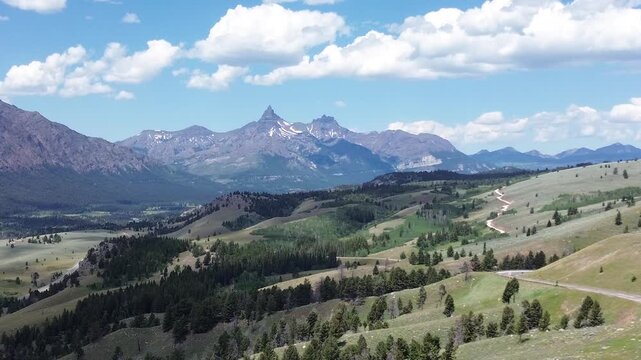 Mountain scenery along the Beartooth Highway in Wyoming. Flying shot pushes in, over a valley towards rugged mountain peaks in the distance.