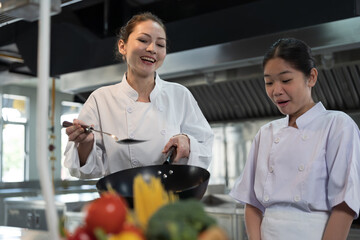 Cooking, Kitchen. Group of young female chef wearing white apron and learning cooking in kitchen at restaurant