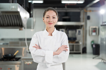 Cooking, Kitchen. Portrait of female chef wearing white apron in kitchen at restaurant