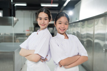Cooking, Kitchen. Portrait of two young female chef wearing white apron in kitchen at restaurant