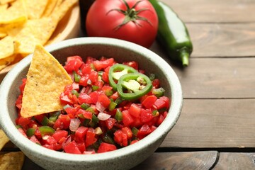 Tasty salsa with nachos and ingredients on wooden table, closeup