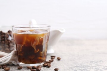 Tasty iced coffee with milk and beans on light table, closeup. Space for text