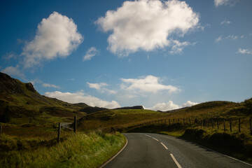 Scenic Winding Road Through Grassy Hills Under Blue Sky in Snowdonia, Wales
