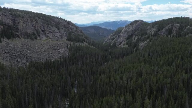 Mountain scenery along the Beartooth Highway in Wyoming. Flying shot pushes in, over a valley towards a notch in the rugged mountain peaks in the distance.