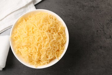 Grated cheese in bowl on grey table, top view. Space for text