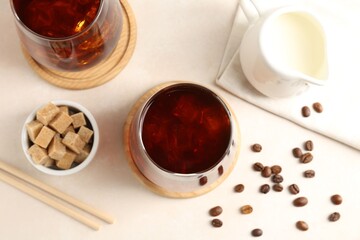 Tasty iced coffee, milk, sugar and beans on white table, flat lay