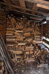 Woodpile of chopped firewood stacked inside a rustic wooden shed