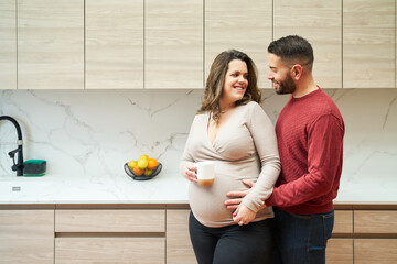 Loving couple expecting baby, embracing pregnancy in kitchen