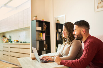 Couple relaxing at home using laptop for online shopping