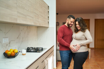 Pregnant couple forming heart hands on baby bump