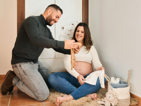 Expecting parents showing baby clothes preparing for new arrival
