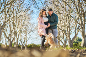 Happy pregnant couple bonding with dog in park