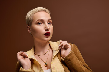 Fashionable young woman showcasing a stunning look against a warm, neutral backdrop © LIGHTFIELD STUDIOS