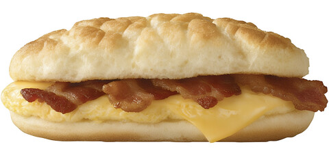 A breakfast sandwich with a bun scrambled eggs crispy bacon strips and melted cheese