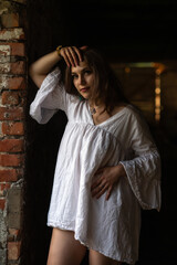 Obraz premium Young woman in a white dress stands playfully in an abandoned building, showcasing her joyful expression and the rustic surroundings, capturing a moment of carefree beauty