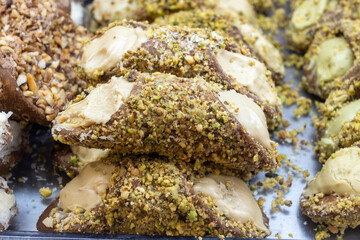 Homemade sweet pastry cannolo sfoglie filled with almond, pistachio, lemon, vanilla, chocolate cream on food market in Palermo, Sicily, Italy