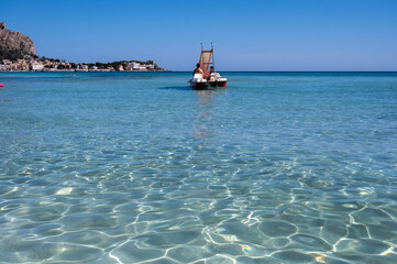 Obraz premium Sunny day on seaside vacation destination, Mondello Beach, near Palermo in Sicily with fine, golden sand, turquoise waters and charming villas, South of Italy
