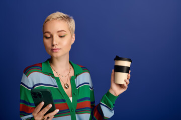 Young fashionable woman enjoys coffee, checking her phone, radiating style and confidence