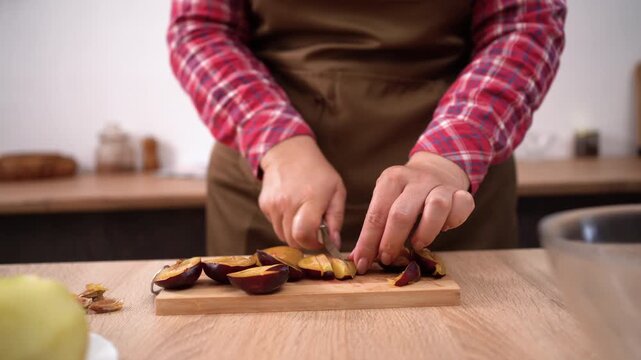 Close-up of Woman cutting plums in the kitchen for plum pie