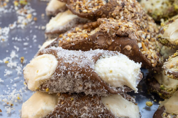 Homemade sweet pastry cannolo sfoglie filled with almond, pistachio, lemon, vanilla, chocolate cream on food market in Palermo, Sicily, Italy